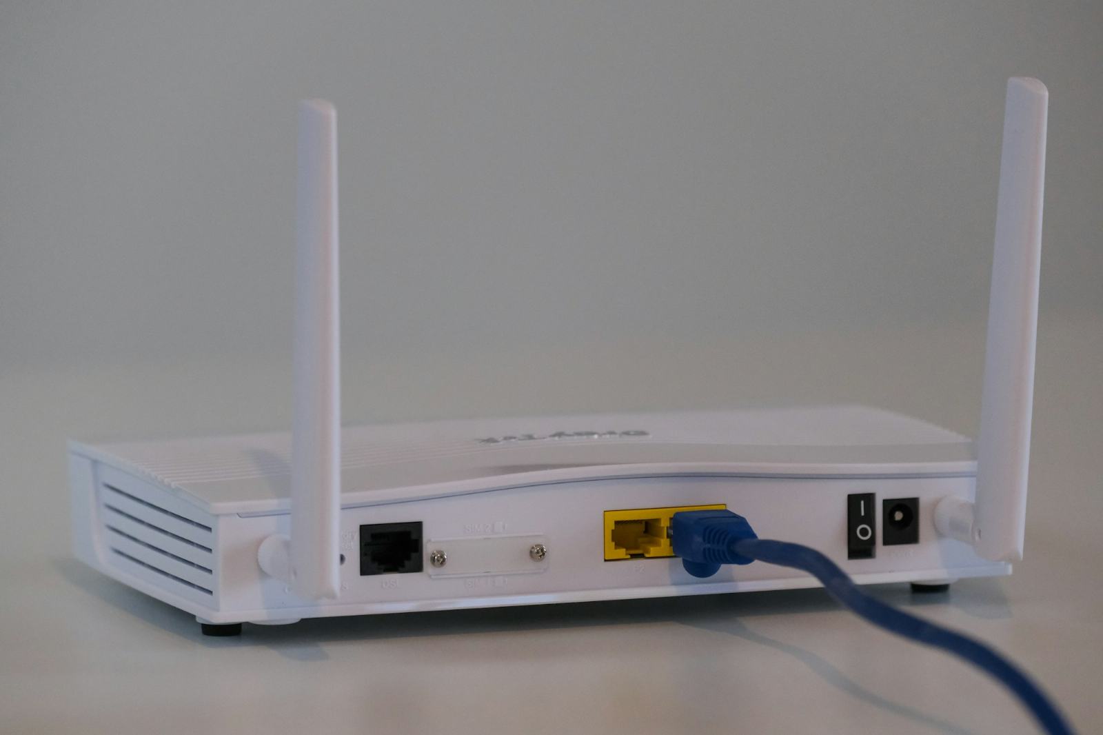 A white WiFi router with an ethernet cable plugged in